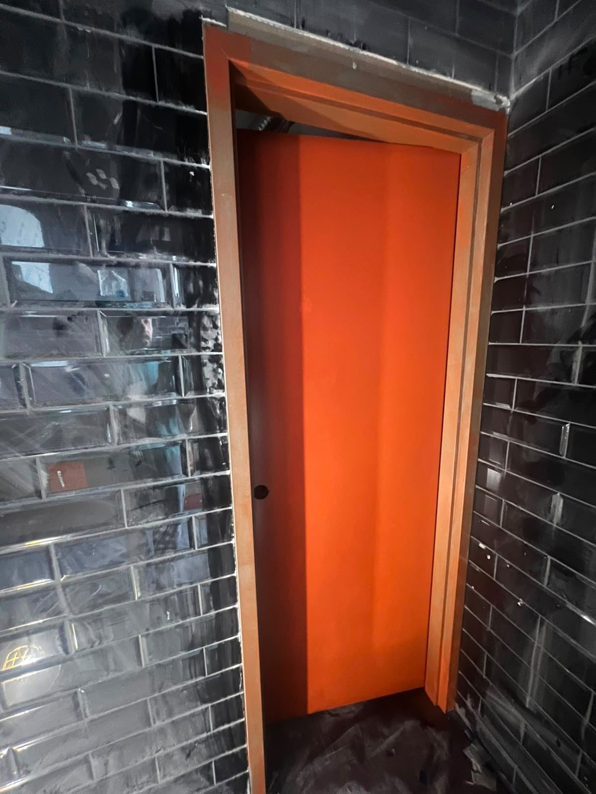 Finished commercial interior with black tile and an orange door