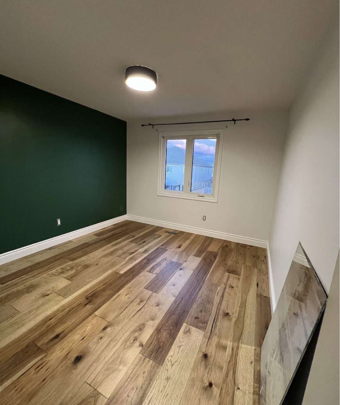 Finished bedroom with new hardwood and a green feature wall